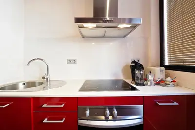 a kitchen with red cabinets and a sink at Sunny Apartments Barcelona in Barcelona