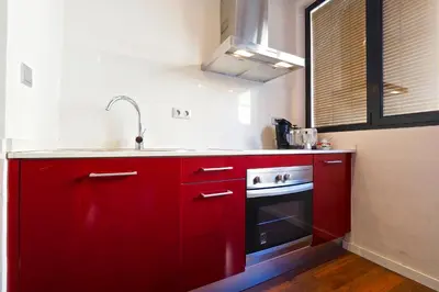 a kitchen with red cabinets and a sink at Sunny Apartments Barcelona in Barcelona