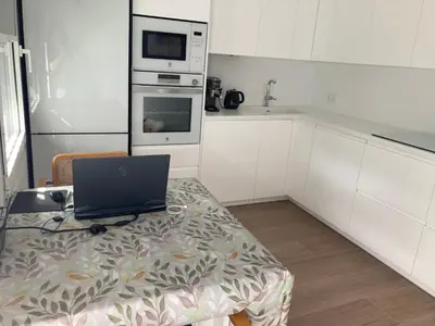 a kitchen with a table with a laptop on it at APARTAMENTO 10 MIN SITGES in Puigmoltó