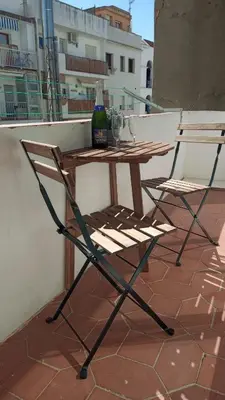 a wooden table and a chair on a balcony at Apartamentospedroche Sitges in Sitges