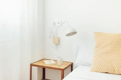 a bed with a lamp and a table with a book at Casa Jam Barcelona in Barcelona