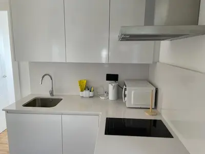 a white kitchen with a sink and a microwave at Apartamento entre mar y montaña in Arenys de Munt