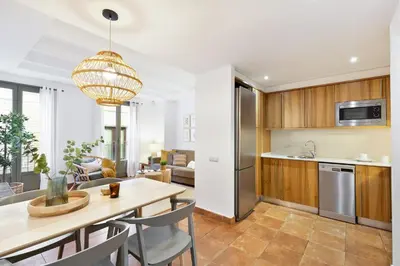 a kitchen and living room with a table and chairs at Columbus Apartment in Barcelona