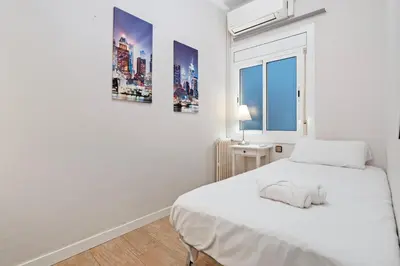 a white bedroom with a bed and a window at Bright 3BR2BA w Balcony in Eixample in Barcelona