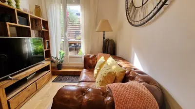 a brown leather couch in a living room with a television at Àtic Trobador in Barcelona