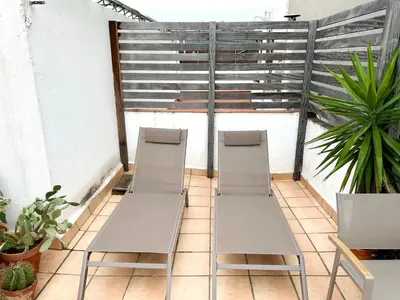 two white chairs sitting on a balcony with plants at Àtic Trobador in Barcelona