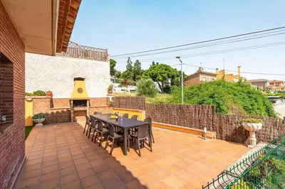 a patio with a table and chairs and a fireplace at Casa rustica con piscina y jardin in Pineda de Mar