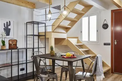a dining room with a table and wooden stairs at BeBarceloner Eixample Duplex Apartments in Barcelona