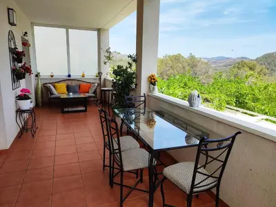 a balcony with a glass table and chairs and a couch at Olivella Bed&breakfast in Olivella