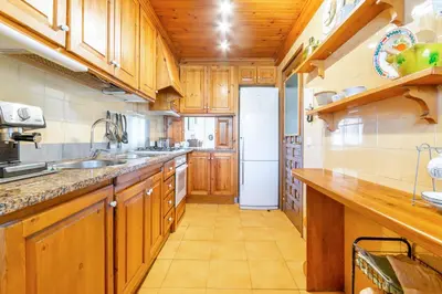 a kitchen with wooden cabinets and a white refrigerator at Paola: Preciosa casa pareada con piscina in Sitges