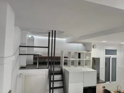 a kitchen with white cabinets and a spiral staircase at La casa del Mamut - Viladecans in Viladecáns