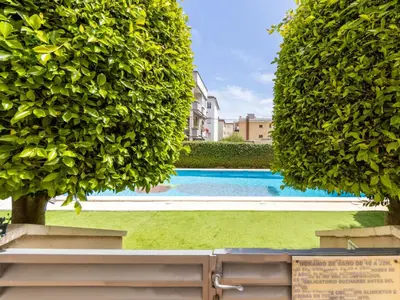 a swimming pool between two large green trees at Apartment Girona by Interhome in Cubelles