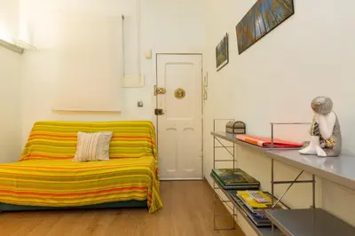a room with a bed with a colorful striped blanket at ApartEasy - Central Barcelona Studio Apartment in Barcelona