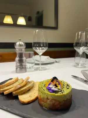 a plate with a piece of bread and some wine glasses at Hostal de la Plaça - Hotel Boutique in Cabrils