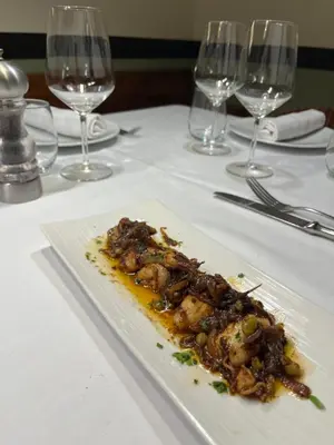 a plate of food on a table with wine glasses at Hostal de la Plaça - Hotel Boutique in Cabrils
