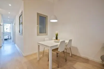 a white dining room with a white table and chairs at BcnStop Sant Pau Suites in Barcelona