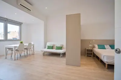 a white room with a table and a bed and chairs at BcnStop Sant Pau Suites in Barcelona