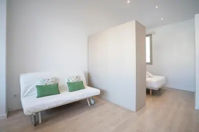 a white chair with two pillows on it in a room at BcnStop Sant Pau Suites in Barcelona