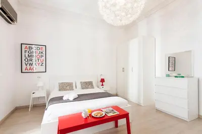 a white bedroom with a bed and a red table at 1554 - AB Passeig de Gràcia Pelai in Barcelona
