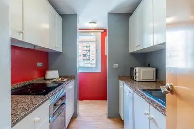 a kitchen with white cabinets and a red wall at 1520 - AB Eixample Sicília Apartment in Barcelona