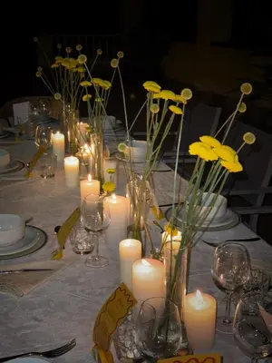 a table with candles and vases with yellow flowers at Villa Golf Sitges in Vilanova i la Geltrú