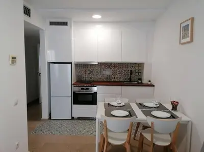 a kitchen with a table with four chairs and a refrigerator at Piso pl 2B, 20min Plaza Cataluña in Sant Adria de Besos