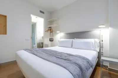 a bedroom with a large white bed with white pillows at Aspasios City Oasis Apartments in Barcelona