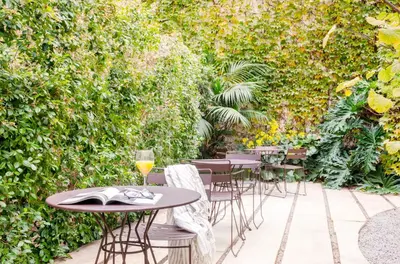 a patio with tables and chairs and a hedge at Aspasios City Oasis Apartments in Barcelona