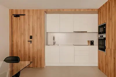 a kitchen with white cabinets and a wooden door at Europa Apartments in Hospitalet de Llobregat