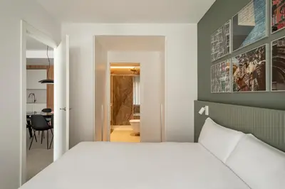 a bedroom with a white bed and a dining room at Europa Apartments in Hospitalet de Llobregat
