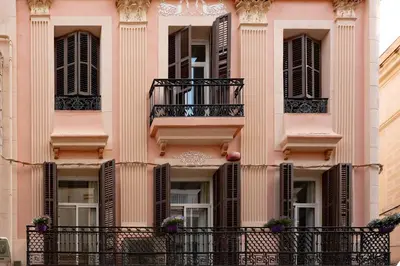 a pink building with windows and a balcony at Antonios Hostal in Sitges