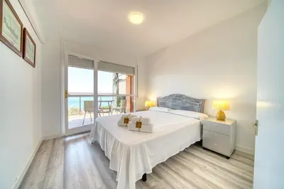 a white bedroom with a bed and a window at HomeHolidaysRentals Aquilone - Costa Barcelona in Pineda de Mar