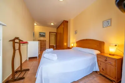 a bedroom with a large white bed and a kitchen at HomeHolidaysRentals Fortuny - Costa Barcelona in Pineda de Mar