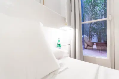 a white room with a window and a bottle on a bed at Hostal Argo in Barcelona