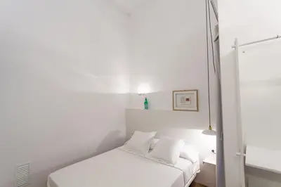 a white bedroom with a bed and a window at Hostal Argo in Barcelona