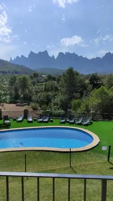 a swimming pool with chairs and mountains in the background at Cal Poldo in Marganell