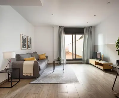a kitchen with white cabinets and a table and chairs at Feelathome Plaza Apartments in Barcelona
