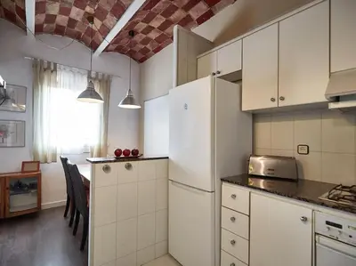a kitchen with white cabinets and a table in it at Bed&BCN Arquimedes Barcelona in Barcelona