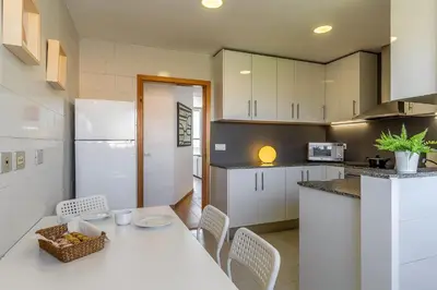 a kitchen with a table and chairs and a white refrigerator at AB Olympic Village III Penthouse in Barcelona