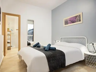 a white bedroom with two beds and a bathroom at Duplex Sagrada Familia 1 in Barcelona