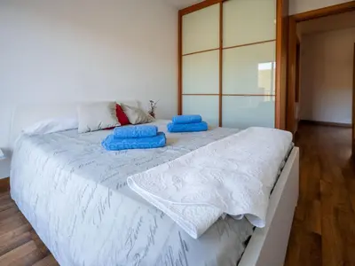 a bedroom with a large white bed with blue pillows on it at Holiday Home Origin by Interhome in Olivella