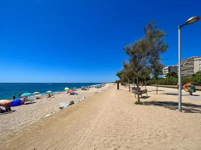 a beach with people laying on the sand and the ocean at Vivalidays Vianka - Pineda de Mar in Pineda de Mar