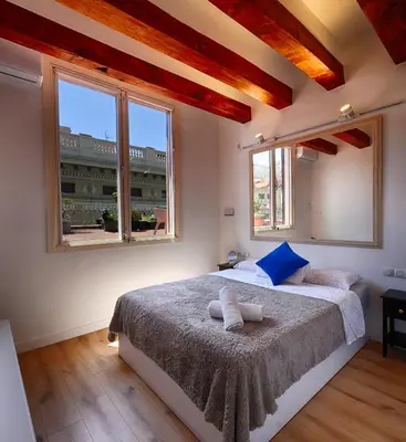 a bedroom with a large bed with two windows at Ramblas Waterfront Stay in Barcelona