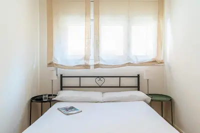 a bedroom with a white bed with a window at AB San Mariano - Park Guell in Barcelona