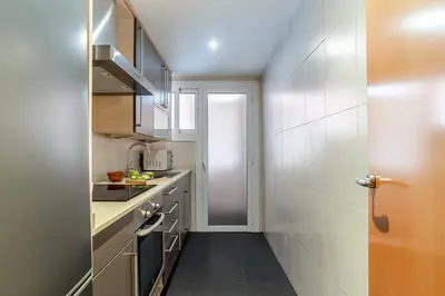 a small kitchen with white cabinets and a door at AB San Mariano - Park Guell in Barcelona