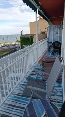 a balcony with chairs and an umbrella and the ocean at Canet playa y centro con free wifi in Canet de Mar