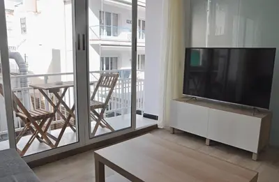 a living room with a flat screen tv and a balcony at Centro Sitges in Sitges