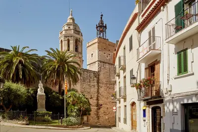 an old building with two towers and palm trees at Centro Sitges in Sitges