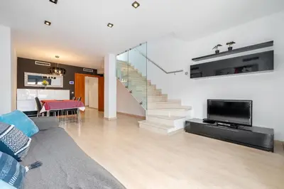 a living room with a couch and a tv and stairs at Hauzify I Apartament Ponent in Pineda de Mar