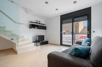 a living room with a couch and a staircase at Hauzify I Apartament Ponent in Pineda de Mar